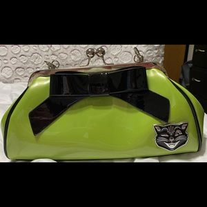 Sourpuss green purse with black bow in front.